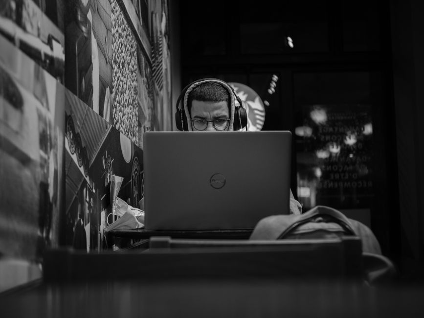 A woman in a home office wearing noise-cancelling headphones while focused on her laptop, highlighting improved productivity.
